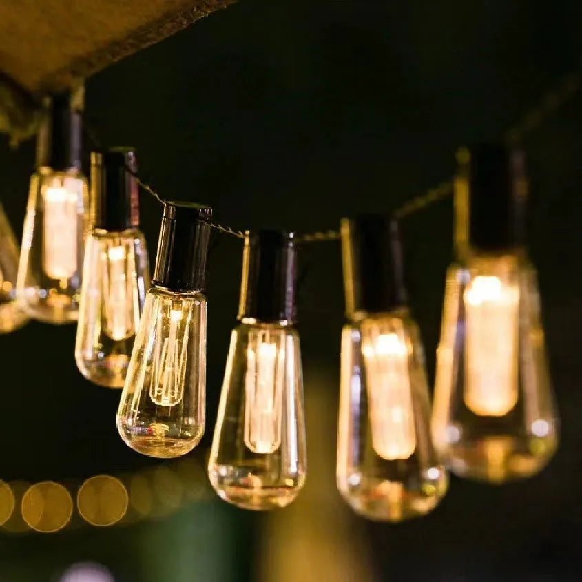 Retro glass infusion bottle shaped outdoor string lights on a patio