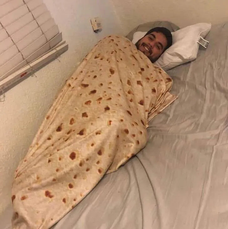 Round coral fleece burrito blanket with food print, shown in a folded pile.
