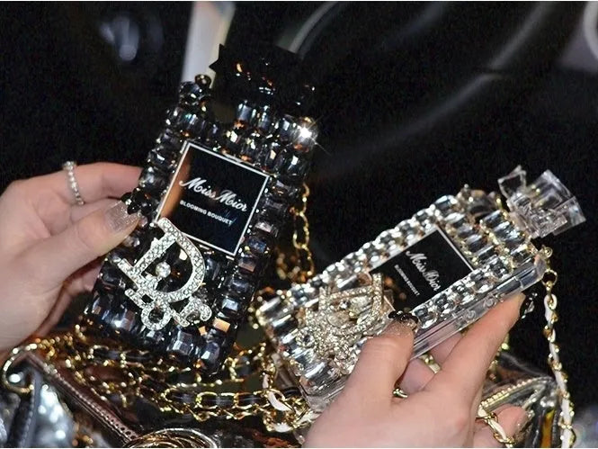 iPhone perfume bottle bow phone case in black with matte TPU shell and gold metal chain holding a perfume bottle charm.