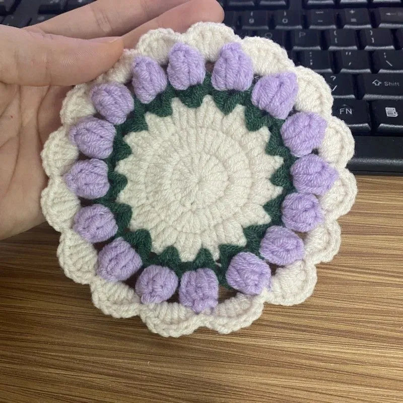 Handmade woven floral coaster in cotton and linen on a wooden table
