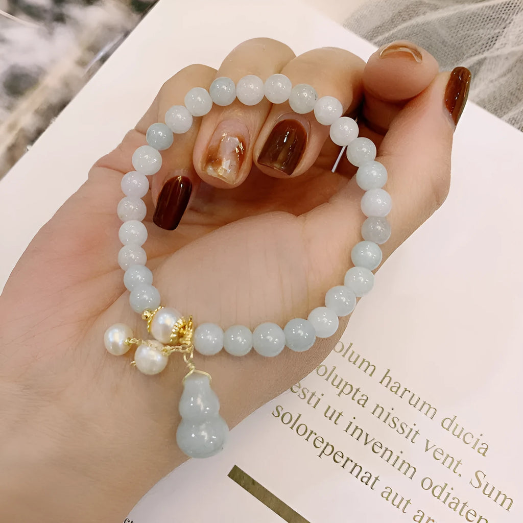 Women's handmade jade bracelet with traditional gourd charm design and pearl accents in natural emerald green colour