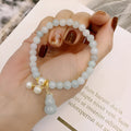Women's handmade jade bracelet with traditional gourd charm design and pearl accents in natural emerald green colour