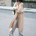Long grey knitted hooded cardigan coat with long sleeves on a hanger.