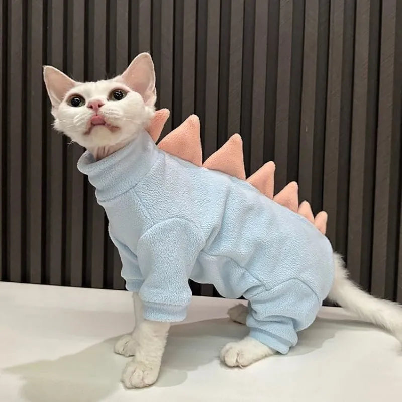 Sphynx cat wearing a green fleece dinosaur costume with a tail and spine spikes