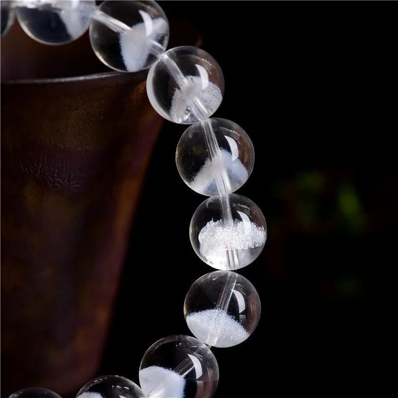 Women's white crystal pyramid bracelet with Ruyi symbol, showing polished beads.