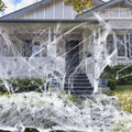 Halloween cotton spider web decoration with white plastic spiders on a dark background