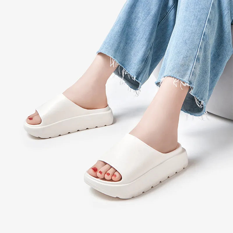 Women's beige fish mouth style slippers with a thick EVA sole on a wooden floor.