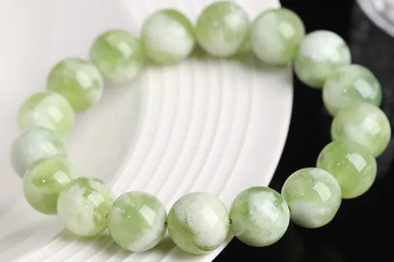 Polished green milk-in-water Xiuyan jade bracelet showing single circle of beads on a wrist.