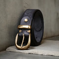Men's brown casual leather belt with a copper pin buckle on a textured background.