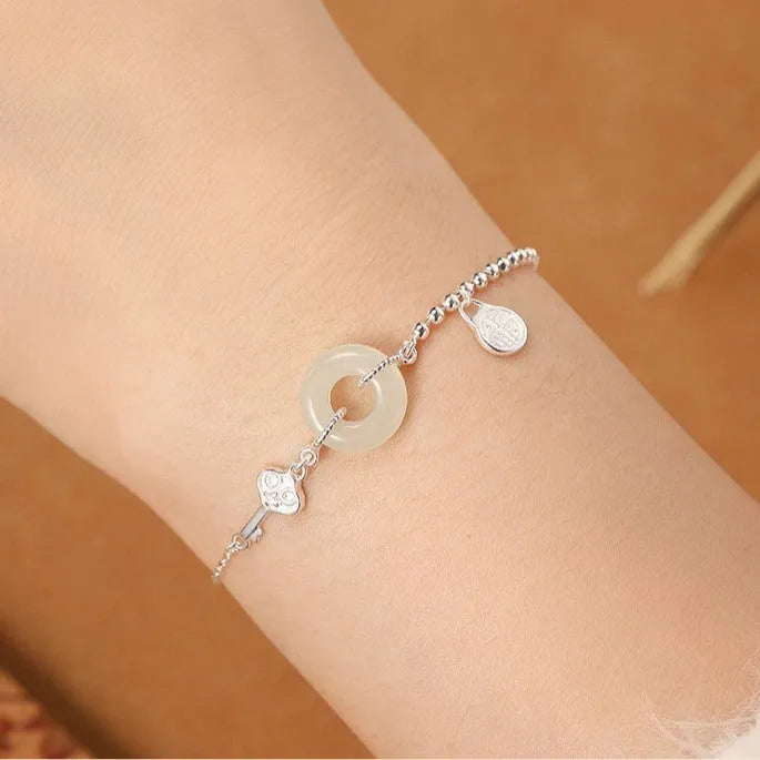 Women's Chinese style silver bracelet with a Hetian jade stone and intricate Peace Buckle design.