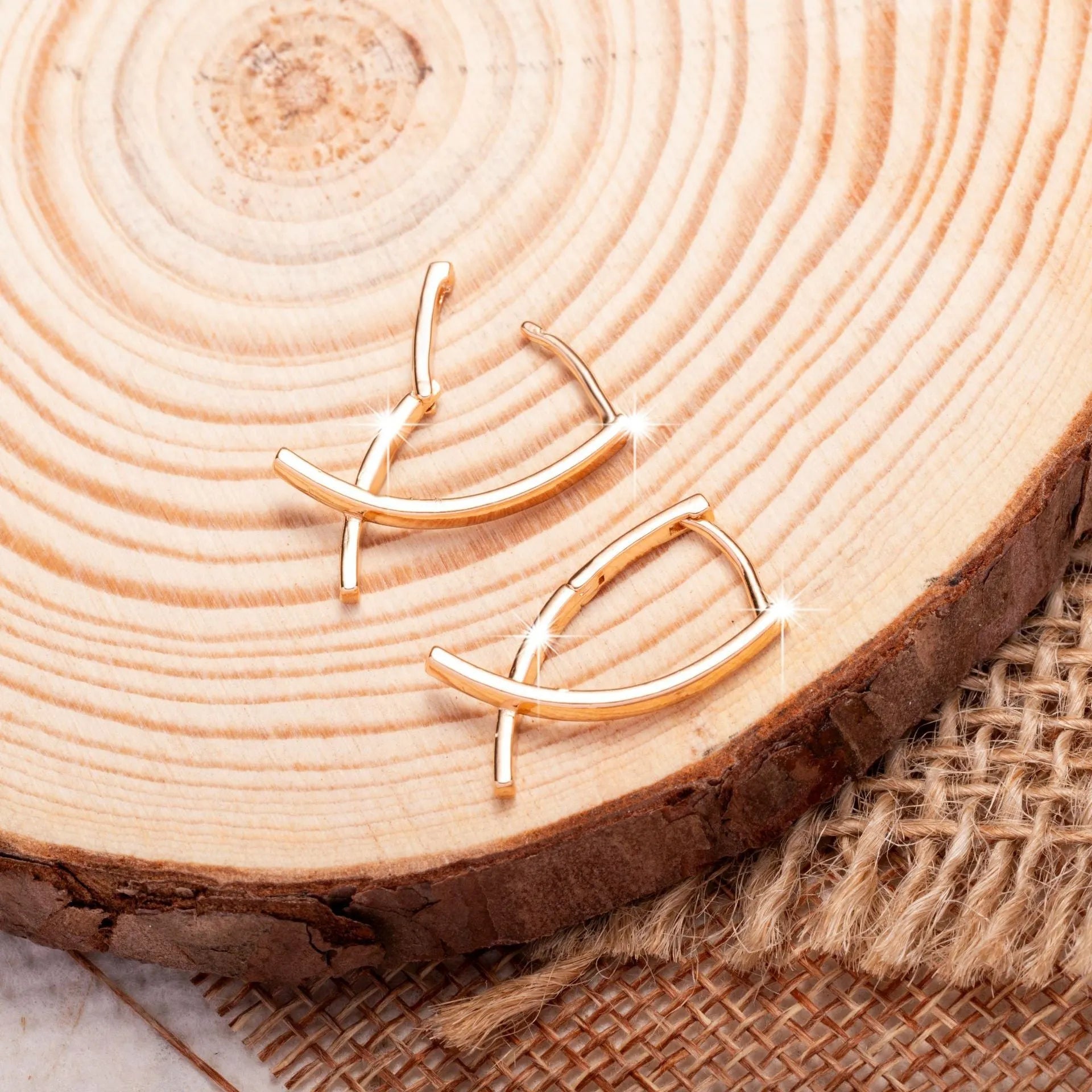 Rose gold coloured cross shaped earrings made from copper metal on a white background.