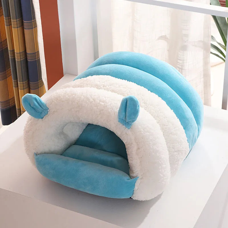Closed cat nest bed in blue colour with removable cushion shown in home setting