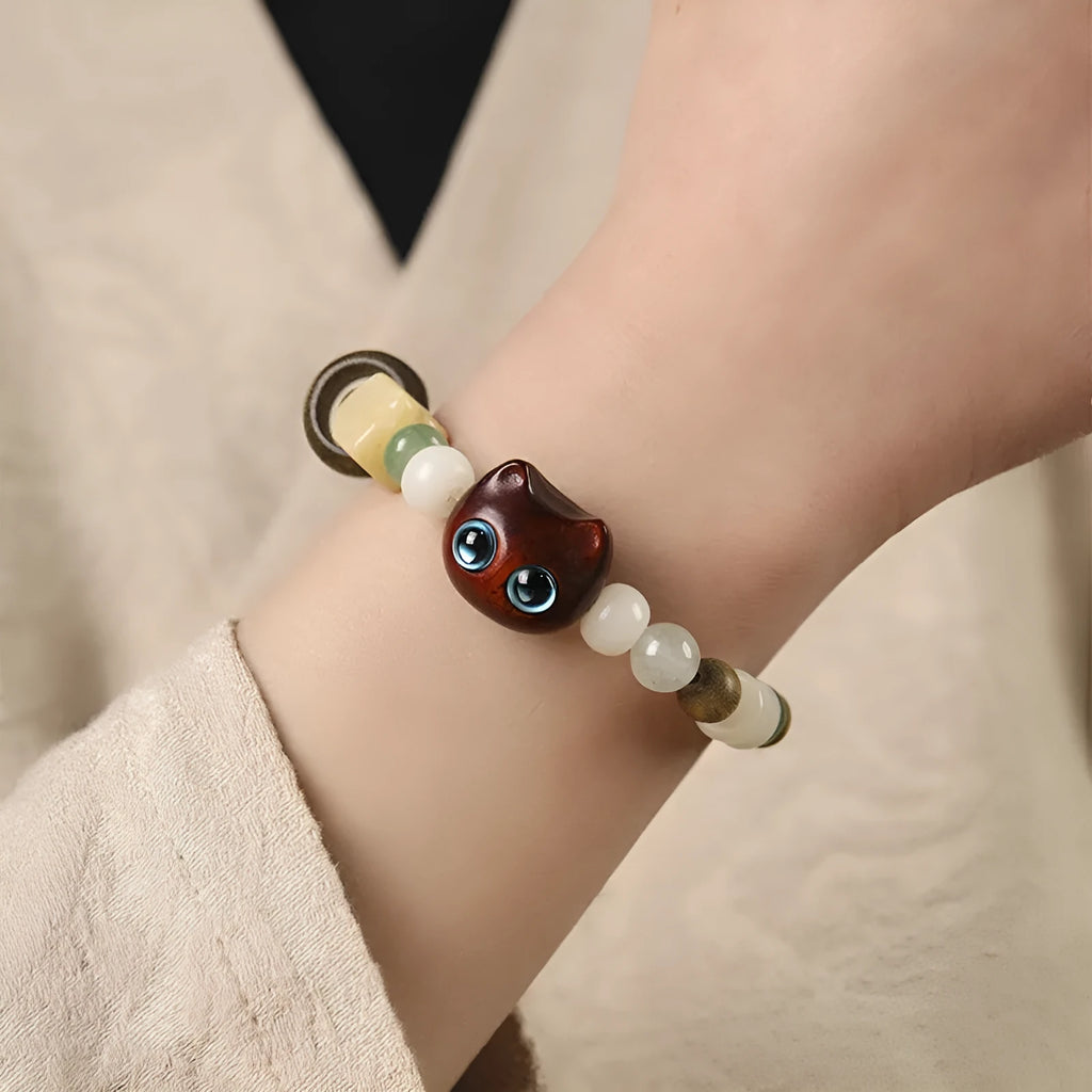 Hand-woven beaded bracelet with a cat's paw charm, jade, and wood beads in a cartoon style.