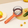 Light green plastic kitchen peeler with built-in storage bucket and scraper function.