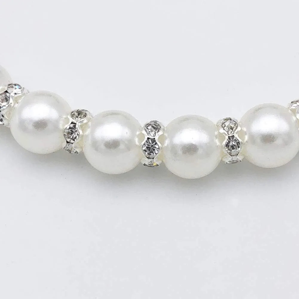 Small dog wearing adjustable pearl and rhinestone necklace with ribbon bow collar