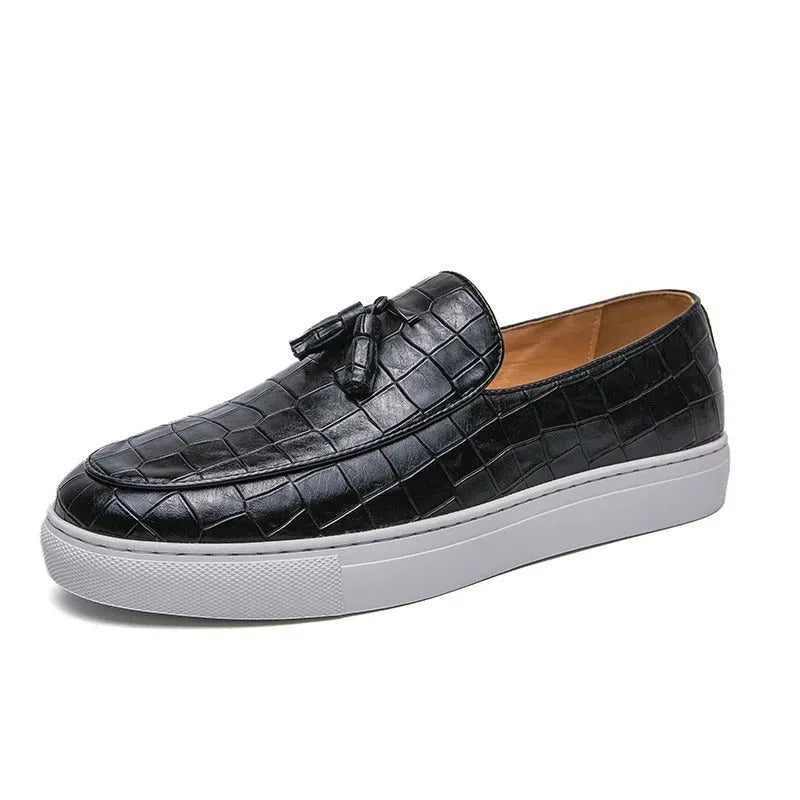 Men's black smart-casual sneakers with a tassel detail on the front, showing a round toe and slip-on style.