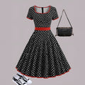A women's polka dot pleated dress with a square collar and zip closure.