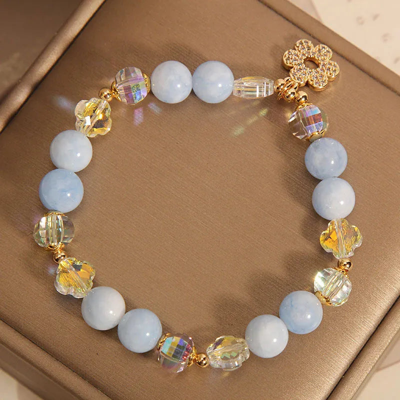 Women's aquamarine crystal bracelet with a four-leaf clover charm and pearl detail.