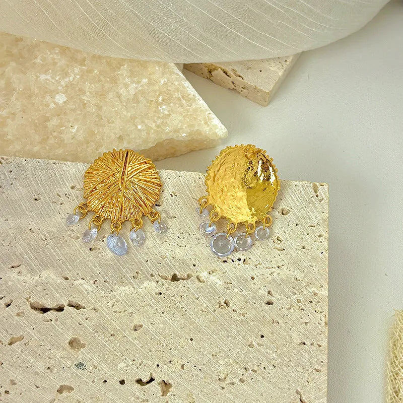 A pair of gold geometric metal earrings with round elements and an electroplated finish.