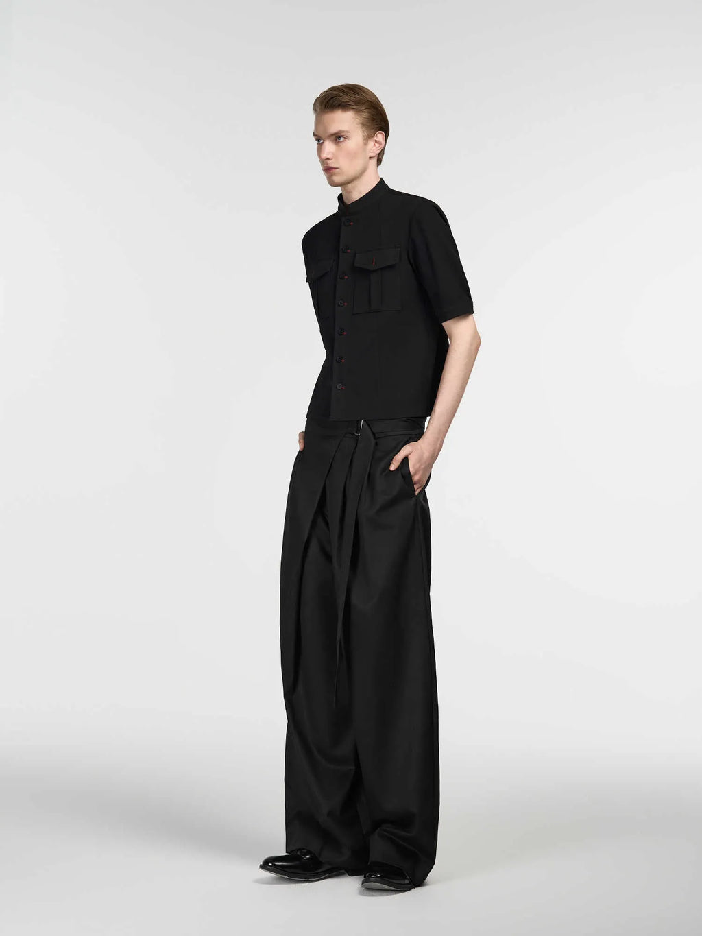 Black straight-leg trousers with a single pleat and adjustable waistband on a hanger.