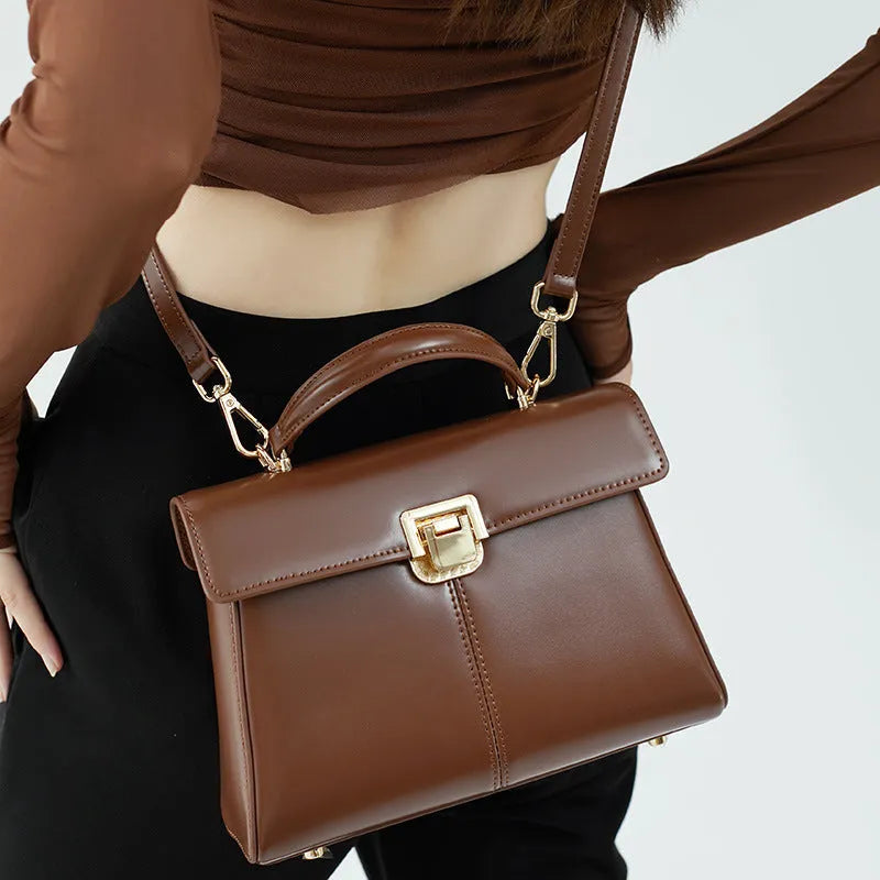 Black genuine leather women's shoulder bag with a vachette clasp, shown open to reveal a zippered hidden pocket.