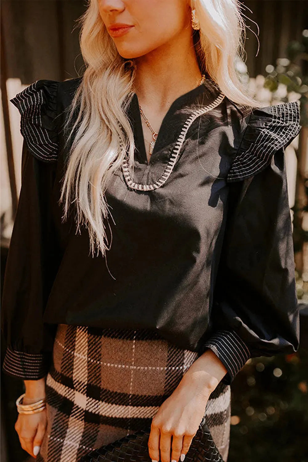 Black V-neck long sleeve blouse with contrast stitching and ruffle trim on sleeves