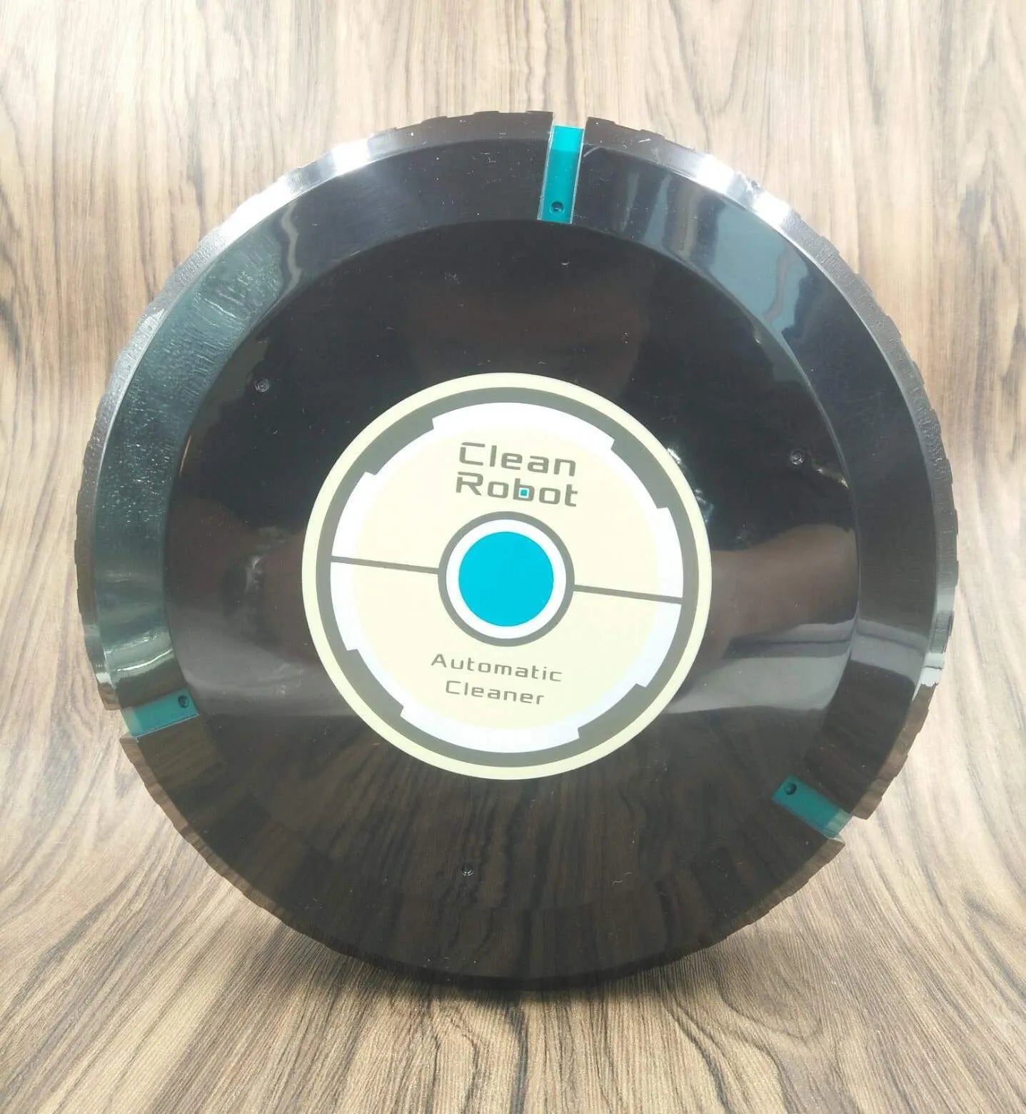 Black and white ABS plastic automatic robot vacuum cleaner on a wooden floor.