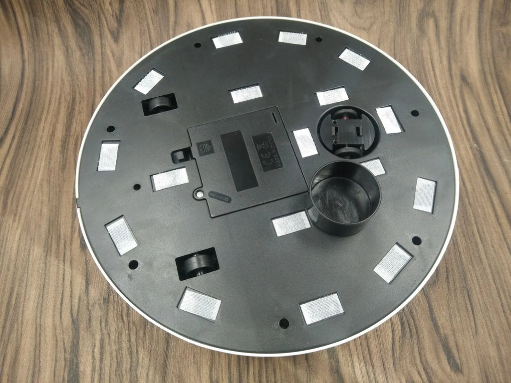 Black and white ABS plastic automatic robot vacuum cleaner on a wooden floor.