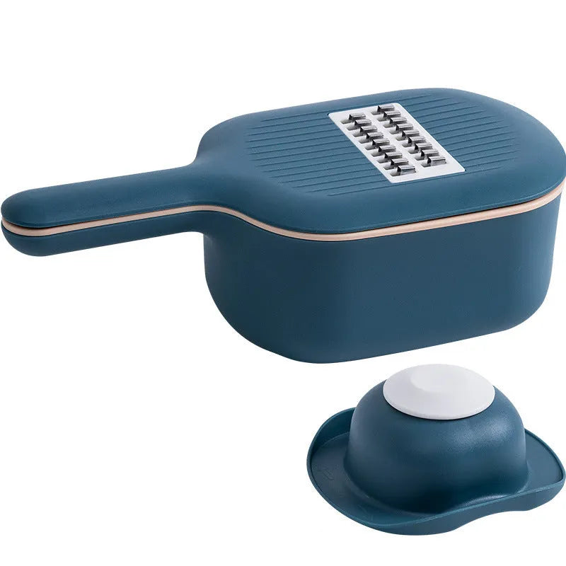 Dark blue vegetable cutter with four stainless steel blades, drain basket, and hand guard on a kitchen worktop