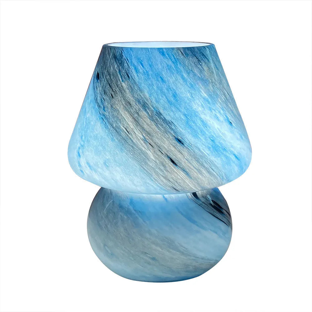 Handmade glass mushroom table lamp in Earth colour on a wooden bedside table with a soft glow