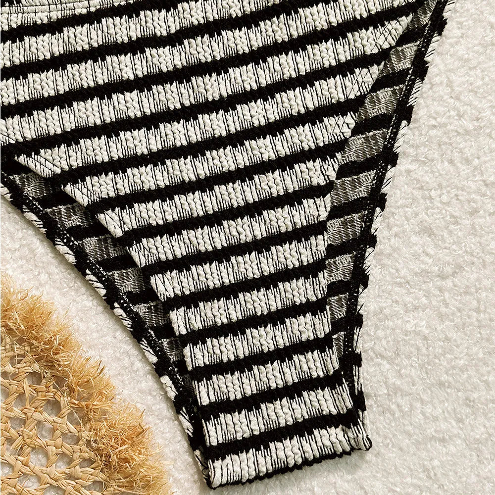 Women's pink and black striped printed bikini swimsuit on a hanger.