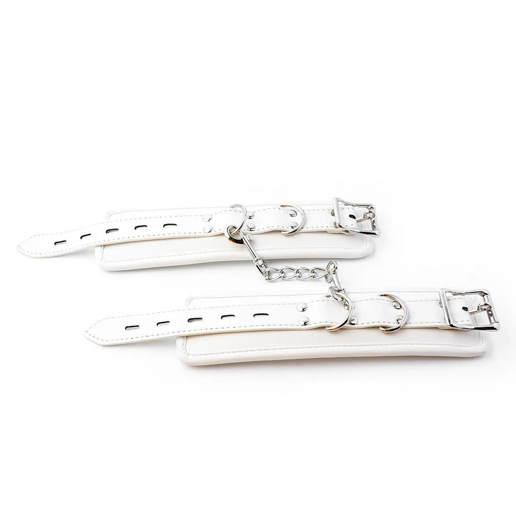 White PU sponge bondage restraint set showing handcuffs, foot cuffs, and a neck scarf on a dark surface.
