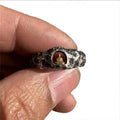 Close-up of a hand-forged copper ring with a Buddha motif and rock texture band on a size 8 finger.