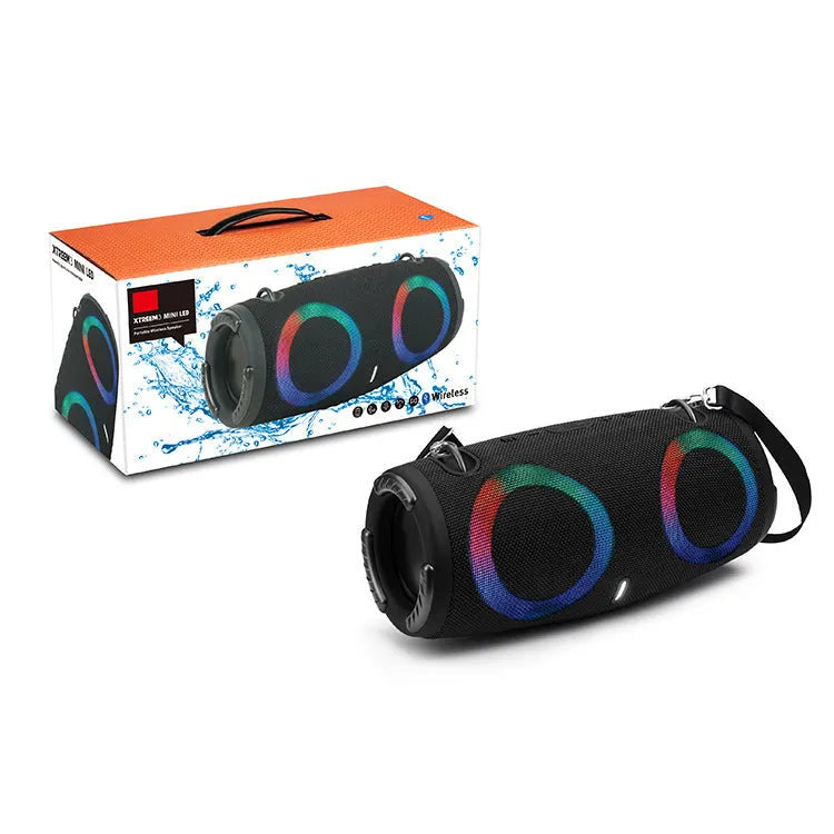 War Drum portable Bluetooth speaker with coloured RGB lights on a table outdoors.