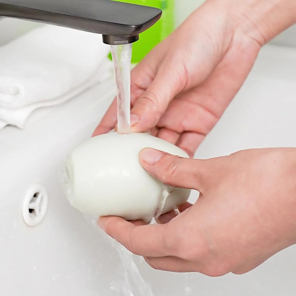 Green and white washable reusable gel lint roller ball for pet hair removal on fabric.