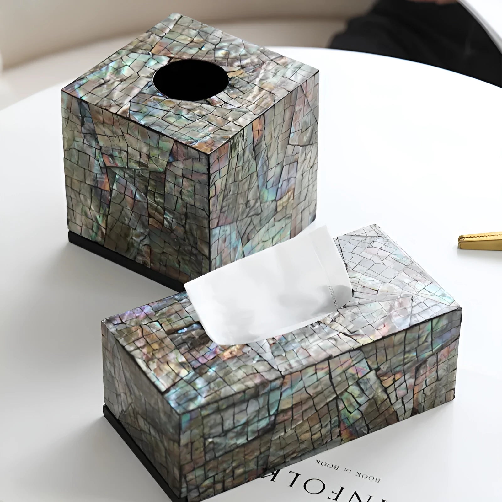 A black square shell storage box with a removable organiser insert on a coffee table.