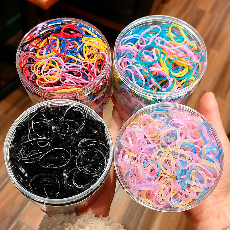 Assorted colourful TPU baby hair ties in a reusable plastic container.