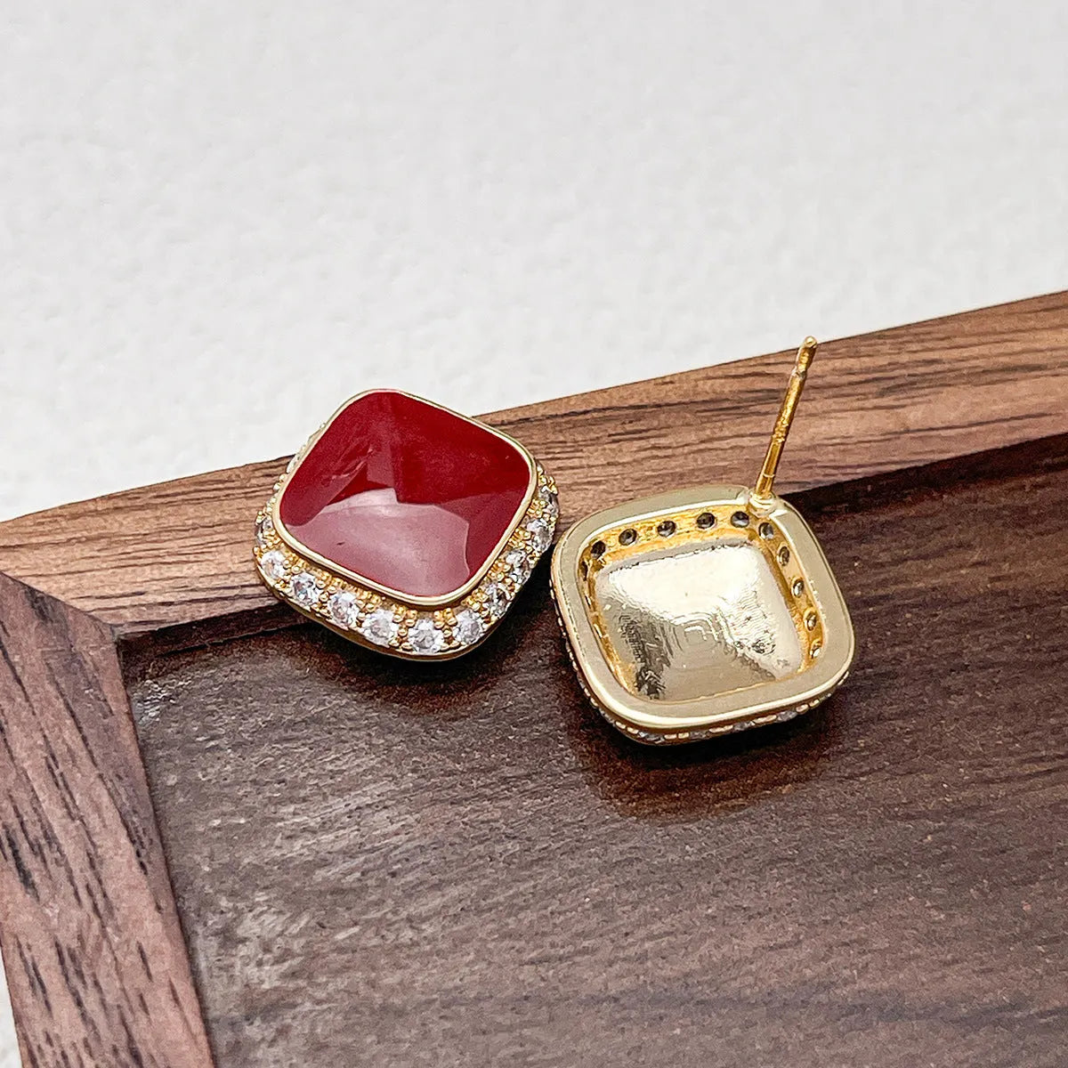 A pair of red geometric square alloy earrings with an inlaid plate design, showing front view.