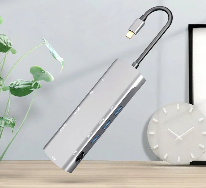 Grey aluminium USB-C docking station showing HDMI, VGA, USB, and charging ports.