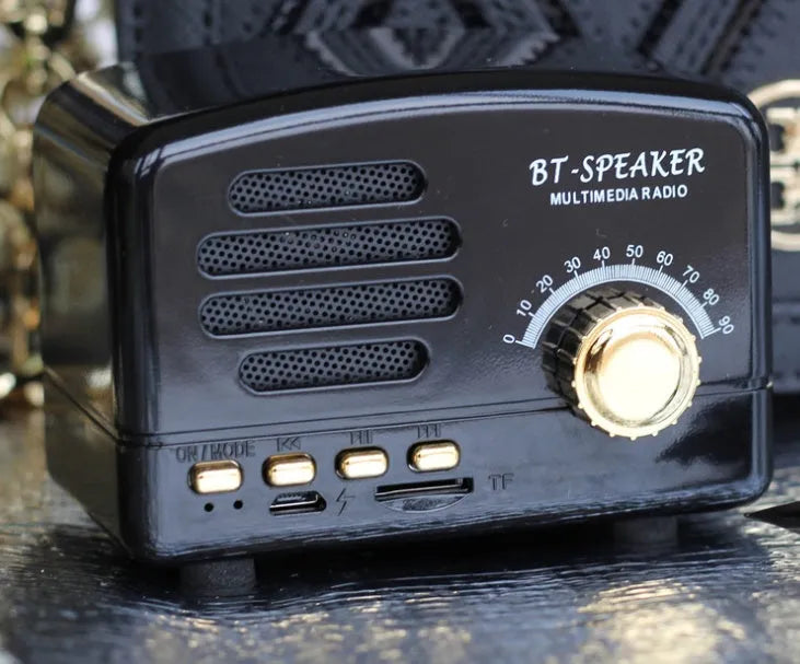 Compact vintage wood finish Bluetooth speaker in black, pink, or wood grain colour on a wooden surface.