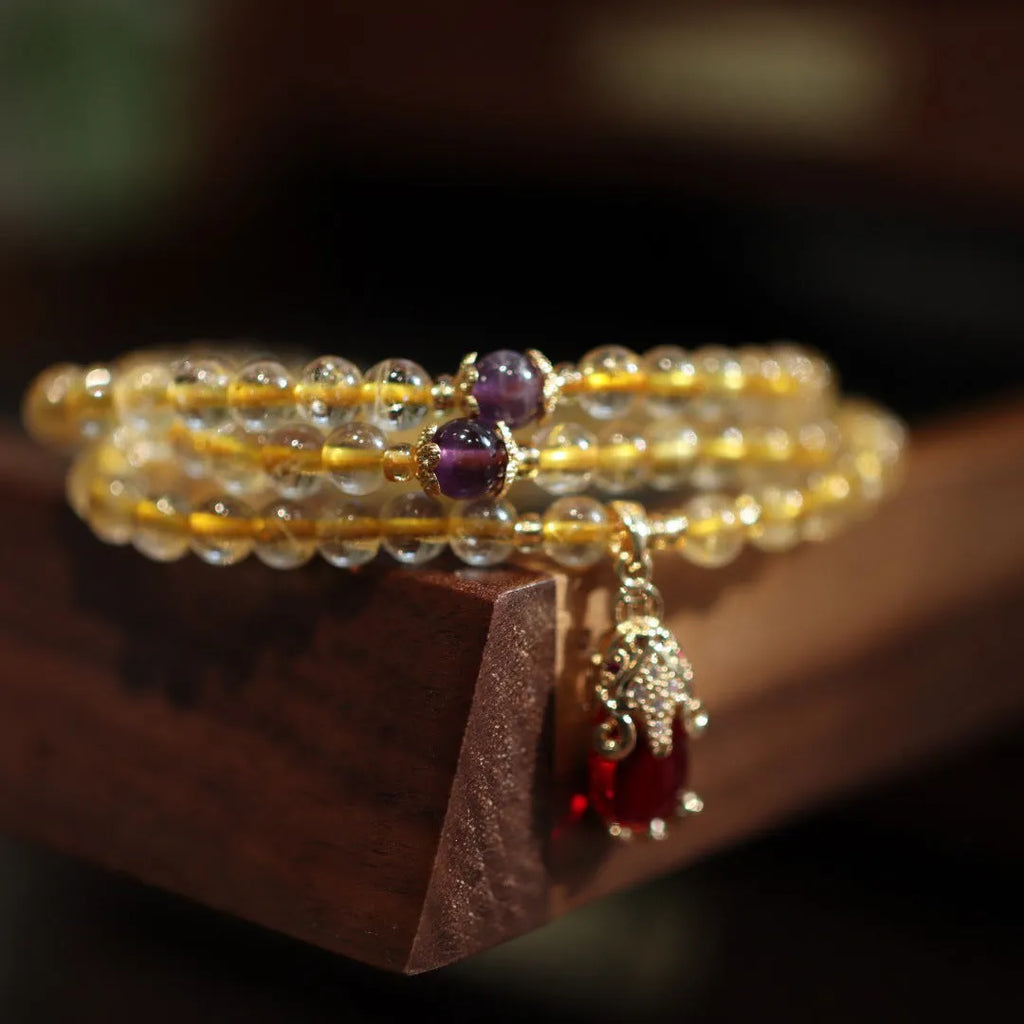 Handmade natural gold rutilated quartz bracelet with three gold circles and a chopsticks charm on a white background.