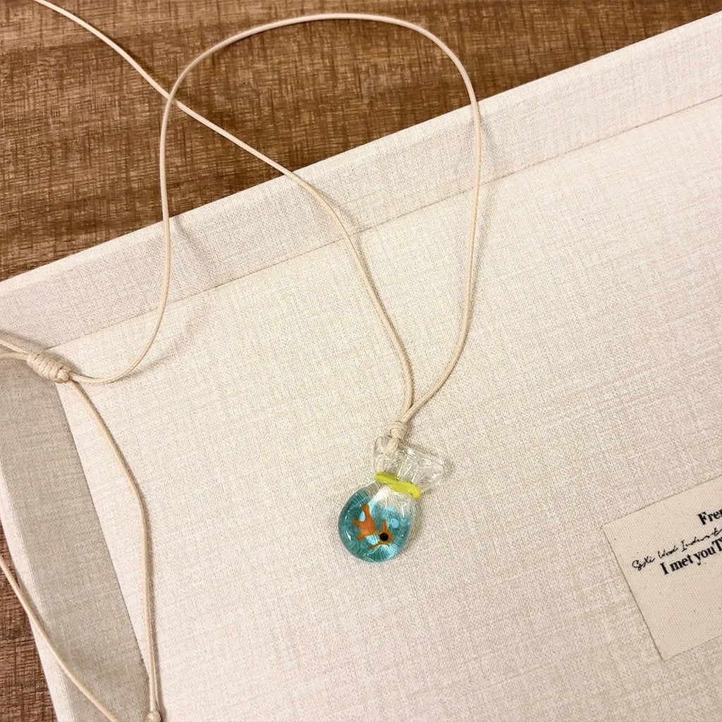 Women's necklace with coloured glaze joker pendant on a beige cotton linen clavicle chain.