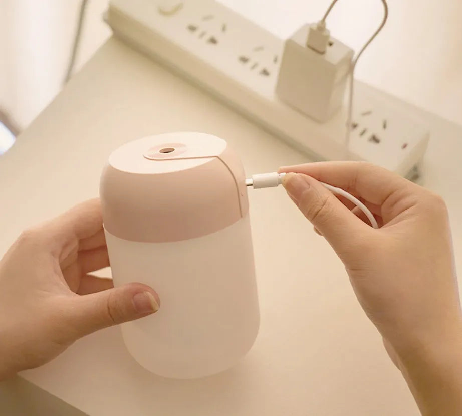White cylindrical USB mini humidifier with mist output and charging cable