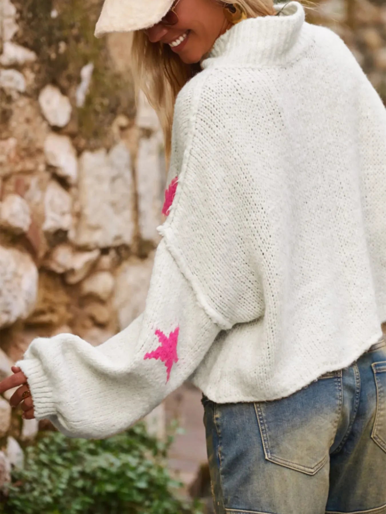 White women's loose turtleneck pullover with a black five-pointed star pattern on the front.