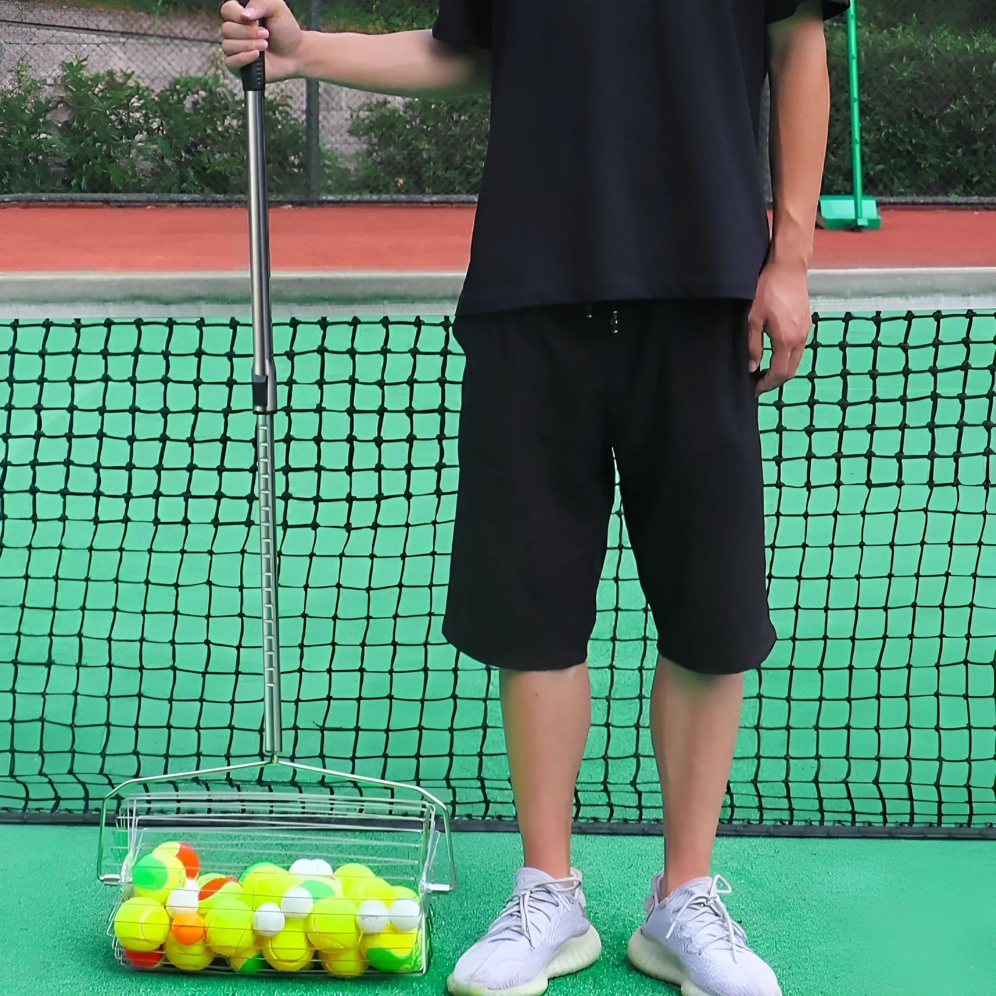 Stainless steel rolling tennis ball picker shown in large size on a tennis court.