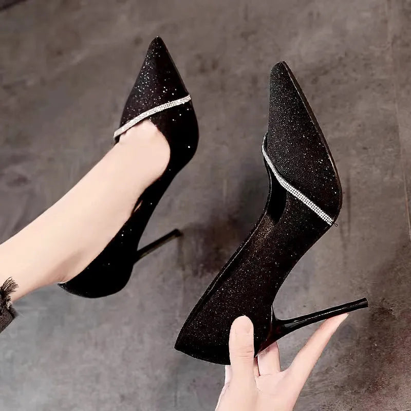 Women's black stiletto high heels with pointed toe and oversleeve design on a white background.