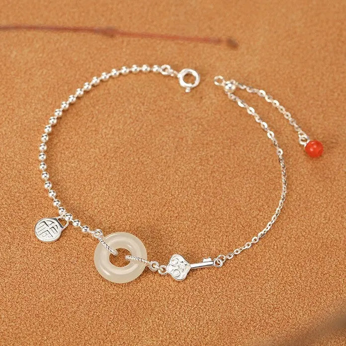 Women's Chinese style silver bracelet with a Hetian jade stone and intricate Peace Buckle design.