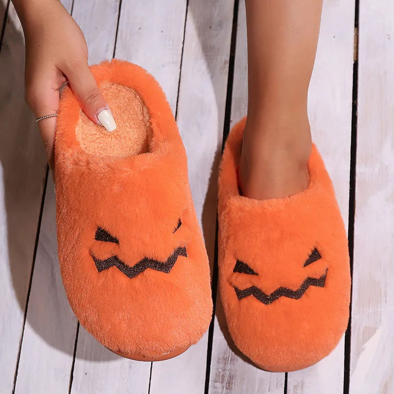 Orange Halloween pumpkin-themed plush slippers with a coral velvet upper and flat heel.