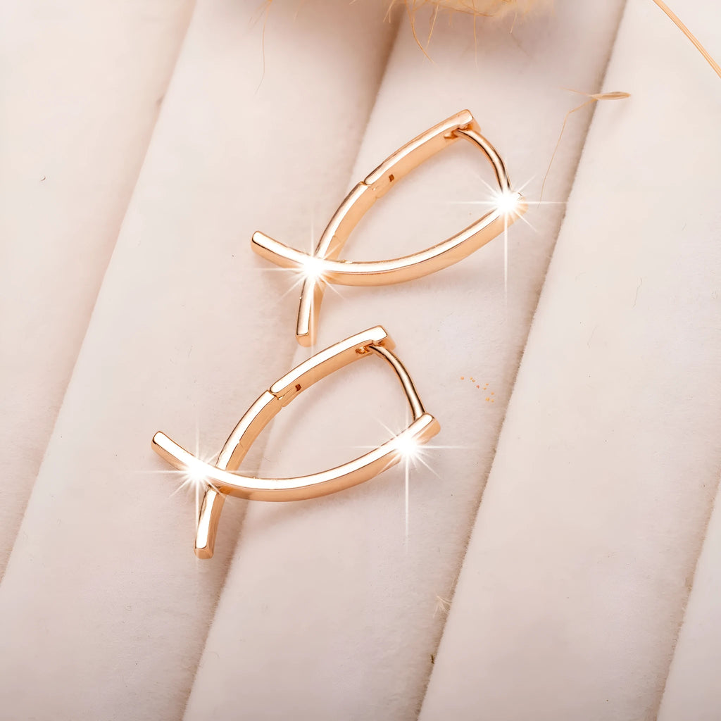 Rose gold coloured cross shaped earrings made from copper metal on a white background.