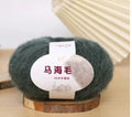 A ball of mohair yarn in a selected colour next to a hand-woven scarf example, showcasing the DIY kit.